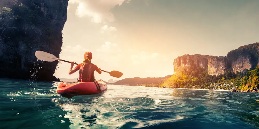 Woman kayaking in a canyon at sunset